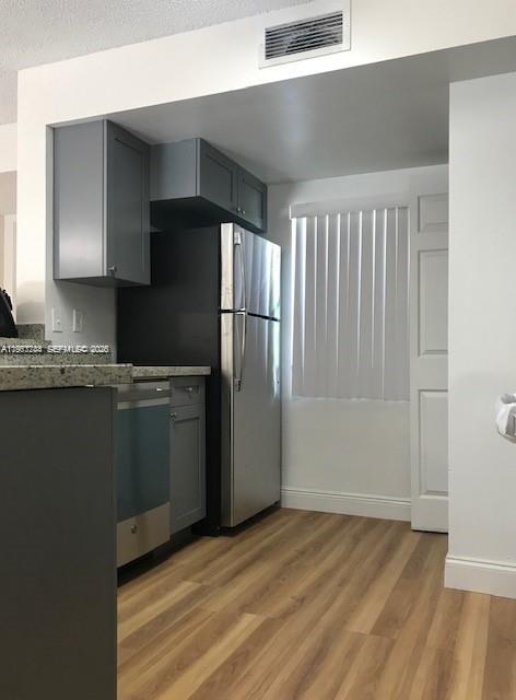 A kitchen features grey cabinets, a stainless steel refrigerator, and light wood-look flooring — 9999 Summerbreeze Dr # 414, Sunrise FL 33322, SUNRISE, FL