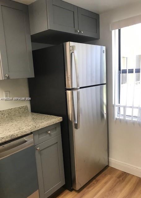 A stainless steel refrigerator stands next to gray cabinets and a granite countertop in a kitchen — 9999 Summerbreeze Dr # 414, Sunrise FL 33322, SUNRISE, FL