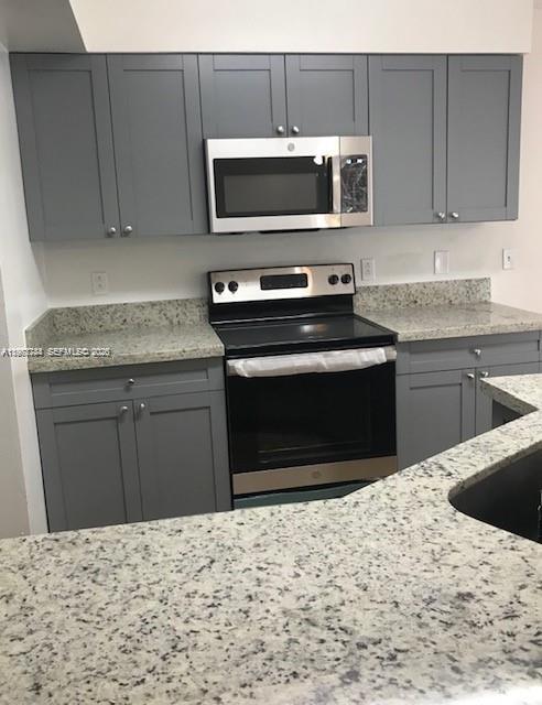 A kitchen features gray cabinets, granite countertops, and stainless steel appliances — 9999 Summerbreeze Dr # 414, Sunrise FL 33322, SUNRISE, FL