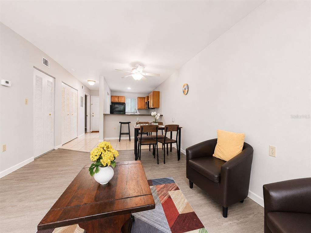 A living room with wood-look flooring, a dining set, and an open kitchen with cabinets — 81 SE 16TH AVENUE UNIT D101, GAINESVILLE, FL