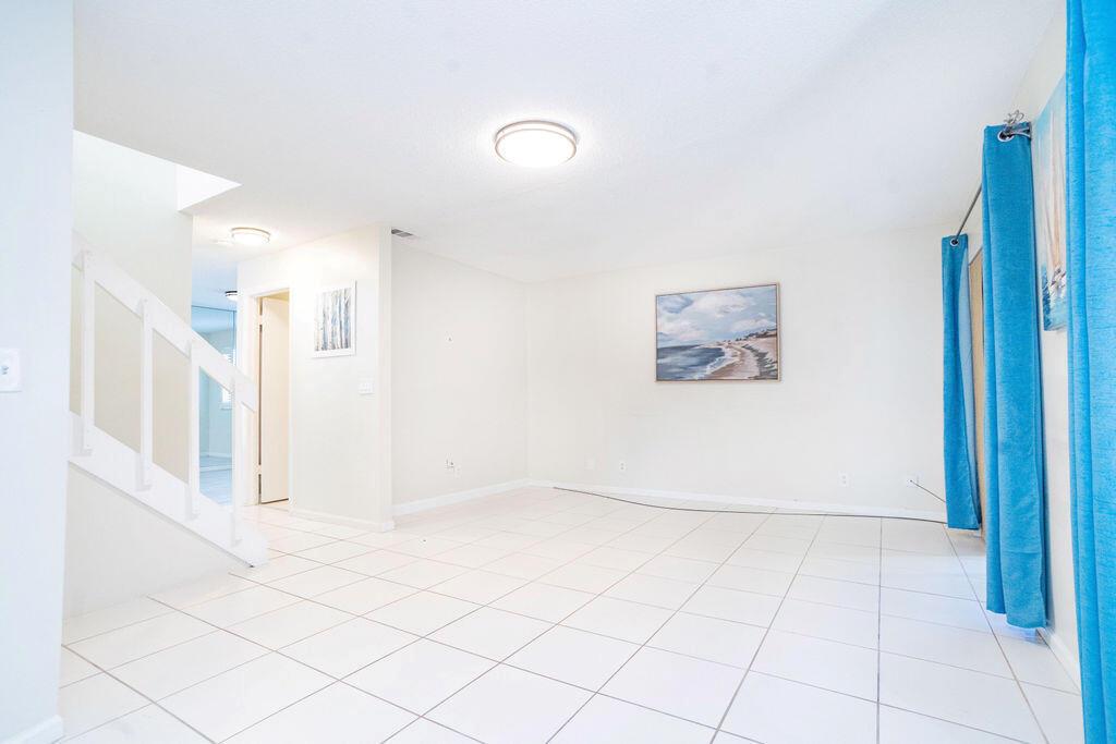 An empty room with white tile floors, a staircase, and blue curtains over a window — 950 S Kanner Hwy Highway # 124, Stuart FL 34994, STUART, FL