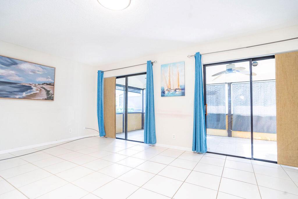A bright room with white tile floors, blue curtains, and sliding glass doors to a patio — 950 S Kanner Hwy Highway # 124, Stuart FL 34994, STUART, FL