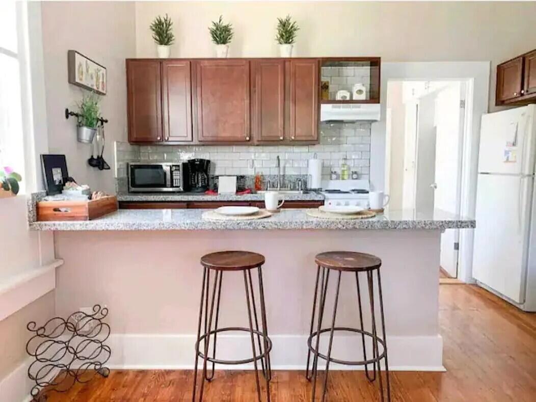 A kitchen features a granite breakfast bar with two stools, wood cabinets, and white appliances — 711 S N Street # 1, FL 33460, FL