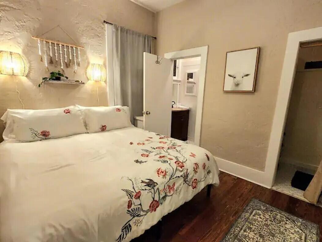 A bedroom with a floral duvet, wall-mounted lamps, and an open doorway to a bathroom — 711 S N Street # 1, FL 33460, FL