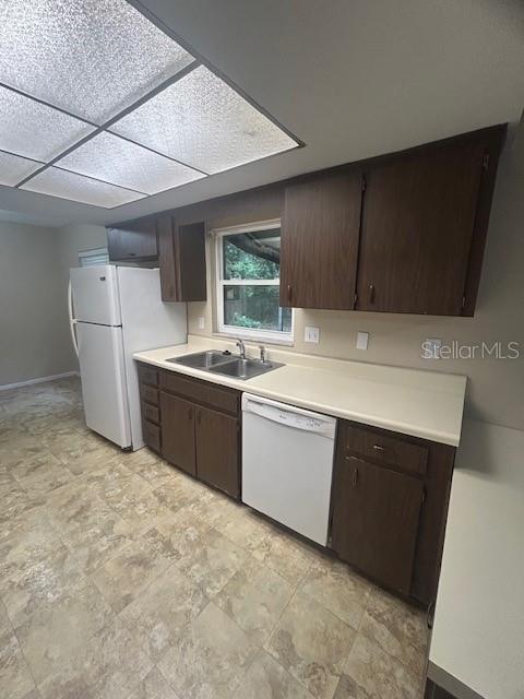 A kitchen features dark wood cabinets, white appliances, a double sink, and light-colored countertops — 1509 CARDINAL STREET, LONGWOOD, FL
