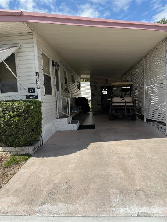 A mobile home exterior features a concrete driveway, a covered carport, and a golf cart — 10297 N LAKE DRIVE UNIT 79, LARGO, FL
