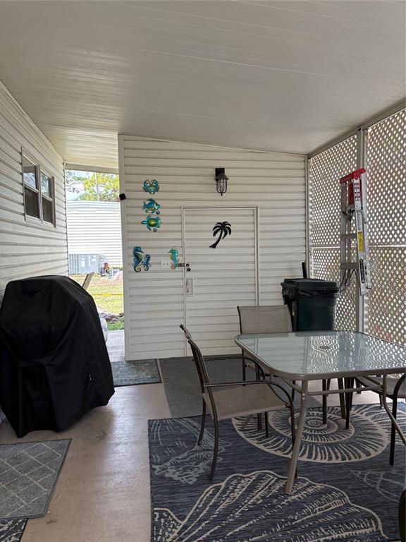 A covered patio features a glass-top table, chairs, a grill, and a storage door — 10297 N LAKE DRIVE UNIT 79, LARGO, FL