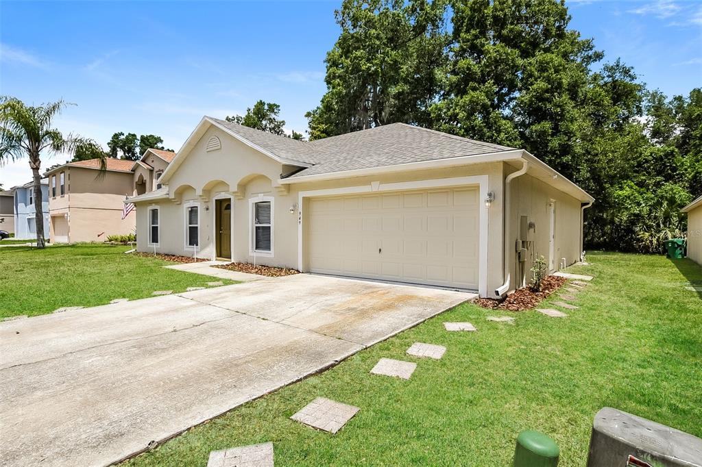 A single-story house with a beige stucco exterior, a two-car garage, and a concrete driveway — 949 CASCADES PARK TRAIL, DELAND, FL