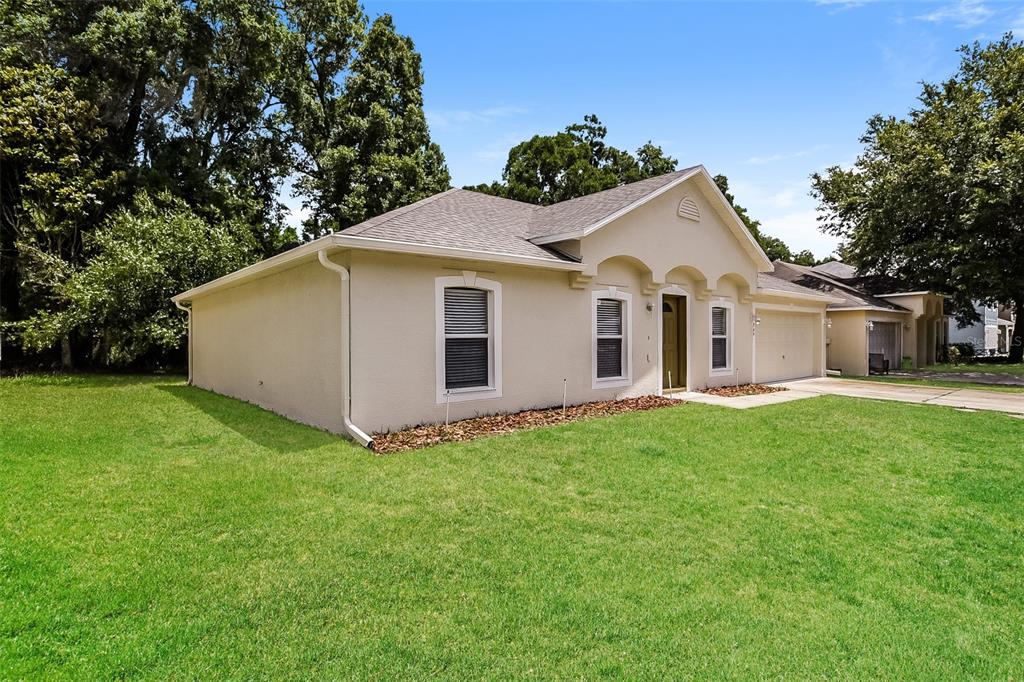 A single-story house with a tan stucco exterior, a shingled roof, and a front-facing garage — 949 CASCADES PARK TRAIL, DELAND, FL