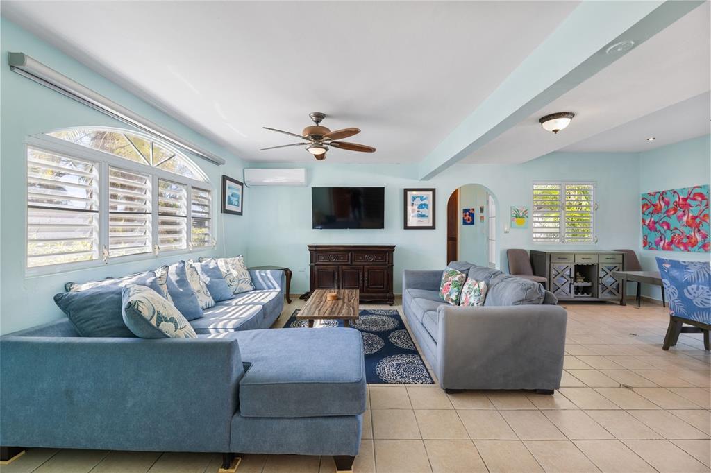 A living room with light blue walls, two blue sofas, tile flooring, and a ceiling fan — 23 CASA CANAL, RINCON, PR
