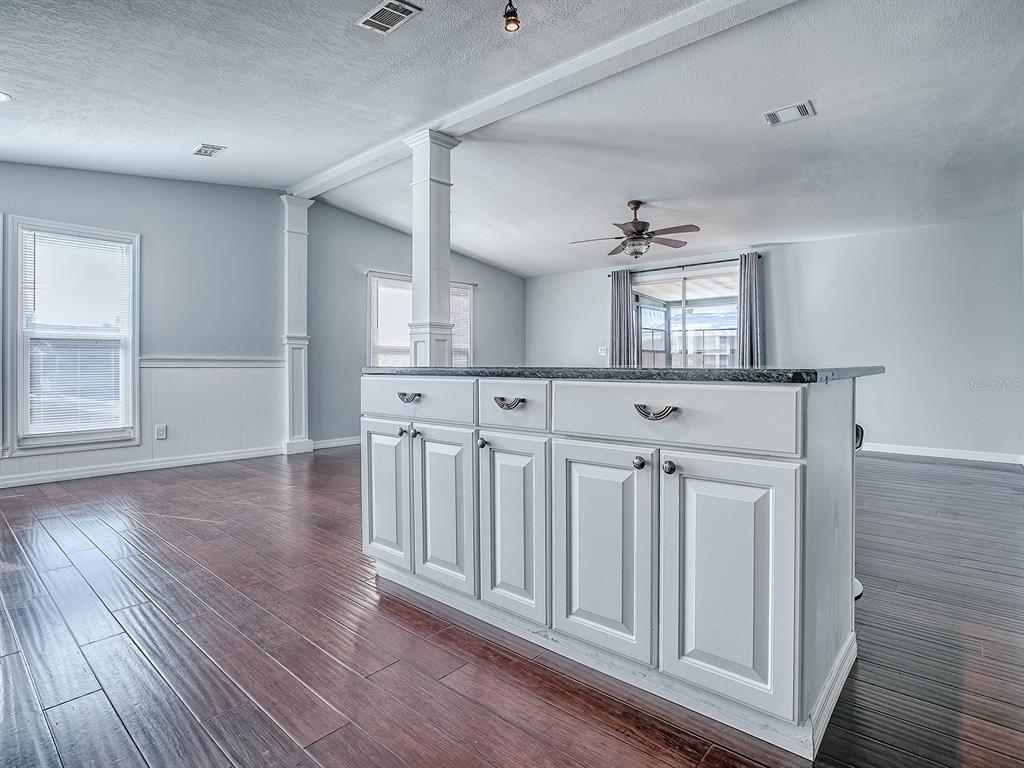 A kitchen island with white cabinets and a dark countertop sits on hardwood floors — 518 SAINT ANDREWS BOULEVARD, LADY LAKE, FL