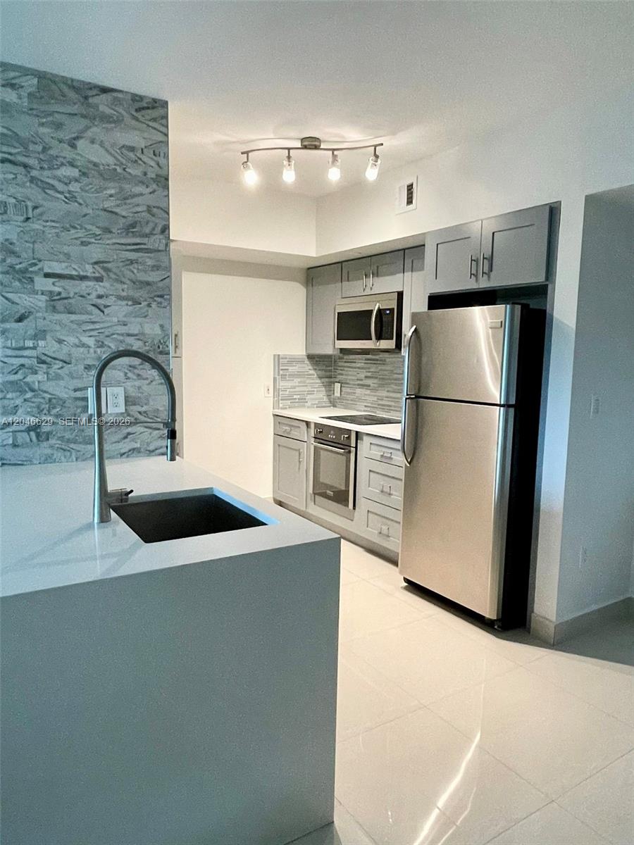 A modern kitchen features gray cabinets, stainless steel appliances, and a white quartz island — 1723 SW 2nd Ave # 801, Miami FL 33129, MIAMI, FL