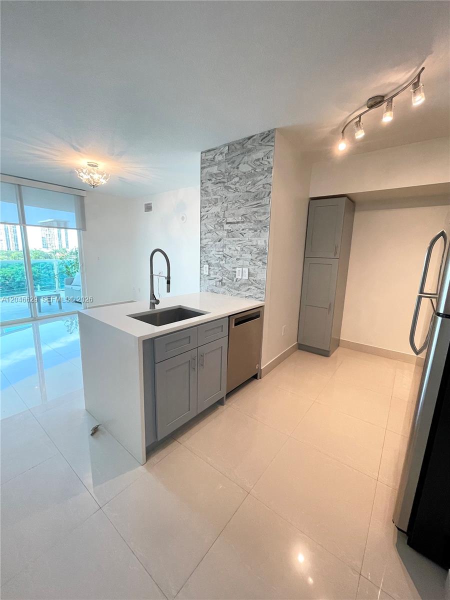 A modern kitchen features gray cabinets, a white island countertop, and a stone-tiled backsplash — 1723 SW 2nd Ave # 801, Miami FL 33129, MIAMI, FL