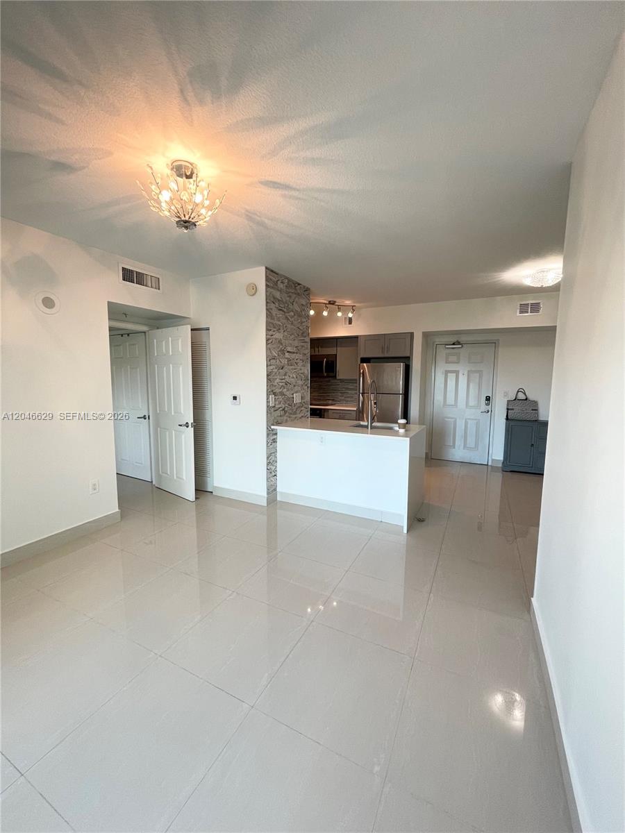 This open-concept living area features light tile flooring, a kitchen island, and stone accent wall — 1723 SW 2nd Ave # 801, Miami FL 33129, MIAMI, FL