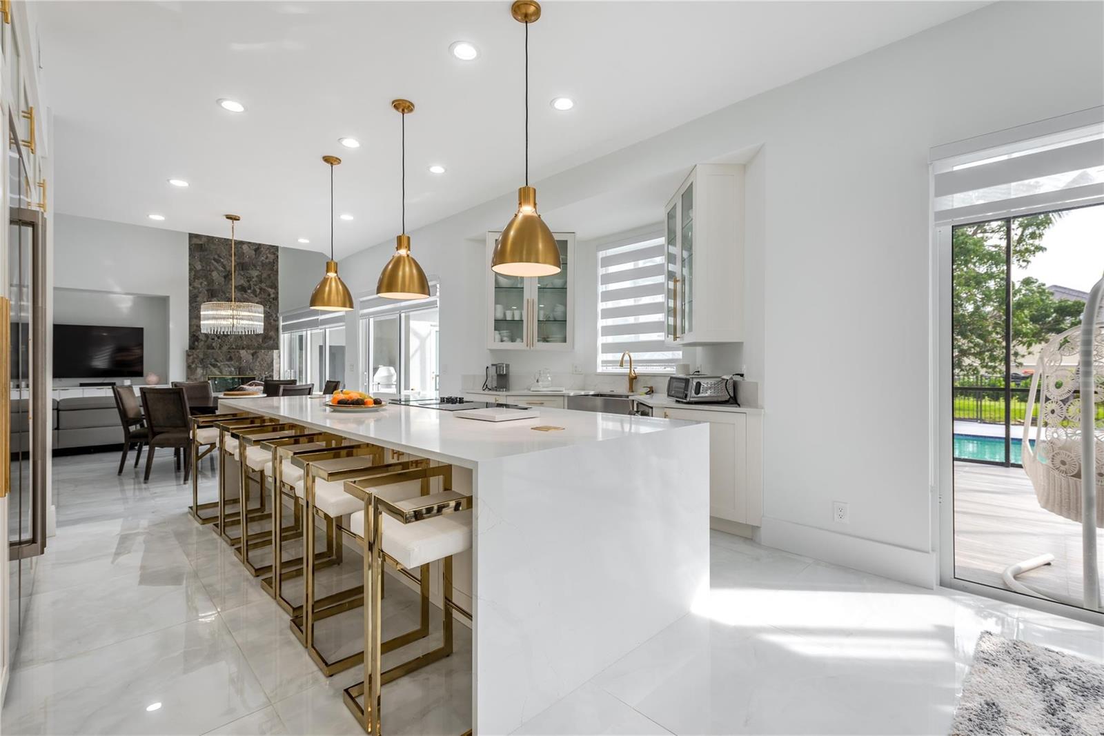 A modern kitchen features a large white quartz island, gold pendant lights, and marble flooring — 2090 Windsock Way, Wellington FL 33414, WELLINGTON, FL