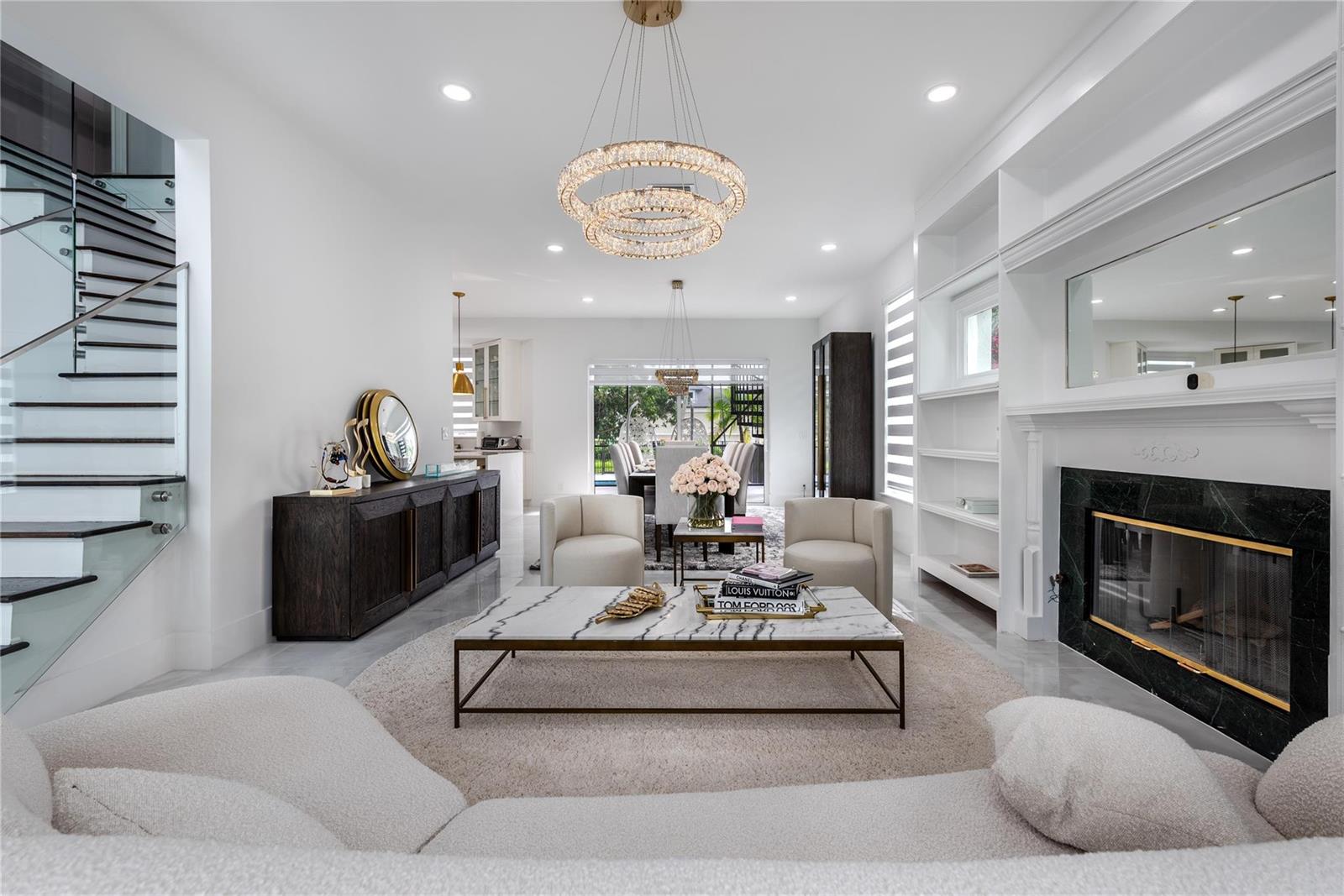 A modern living room features a marble coffee table, fireplace, and a glass-railed staircase — 2090 Windsock Way, Wellington FL 33414, WELLINGTON, FL