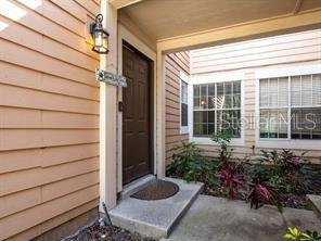 A brown front door is set within a covered entryway featuring light-colored horizontal siding — 713 SANDY COURT UNIT 375, ALTAMONTE SPRINGS, FL