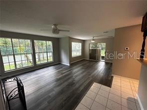 A living room features dark wood-look flooring, large windows, and a ceiling fan — 713 SANDY COURT UNIT 375, ALTAMONTE SPRINGS, FL