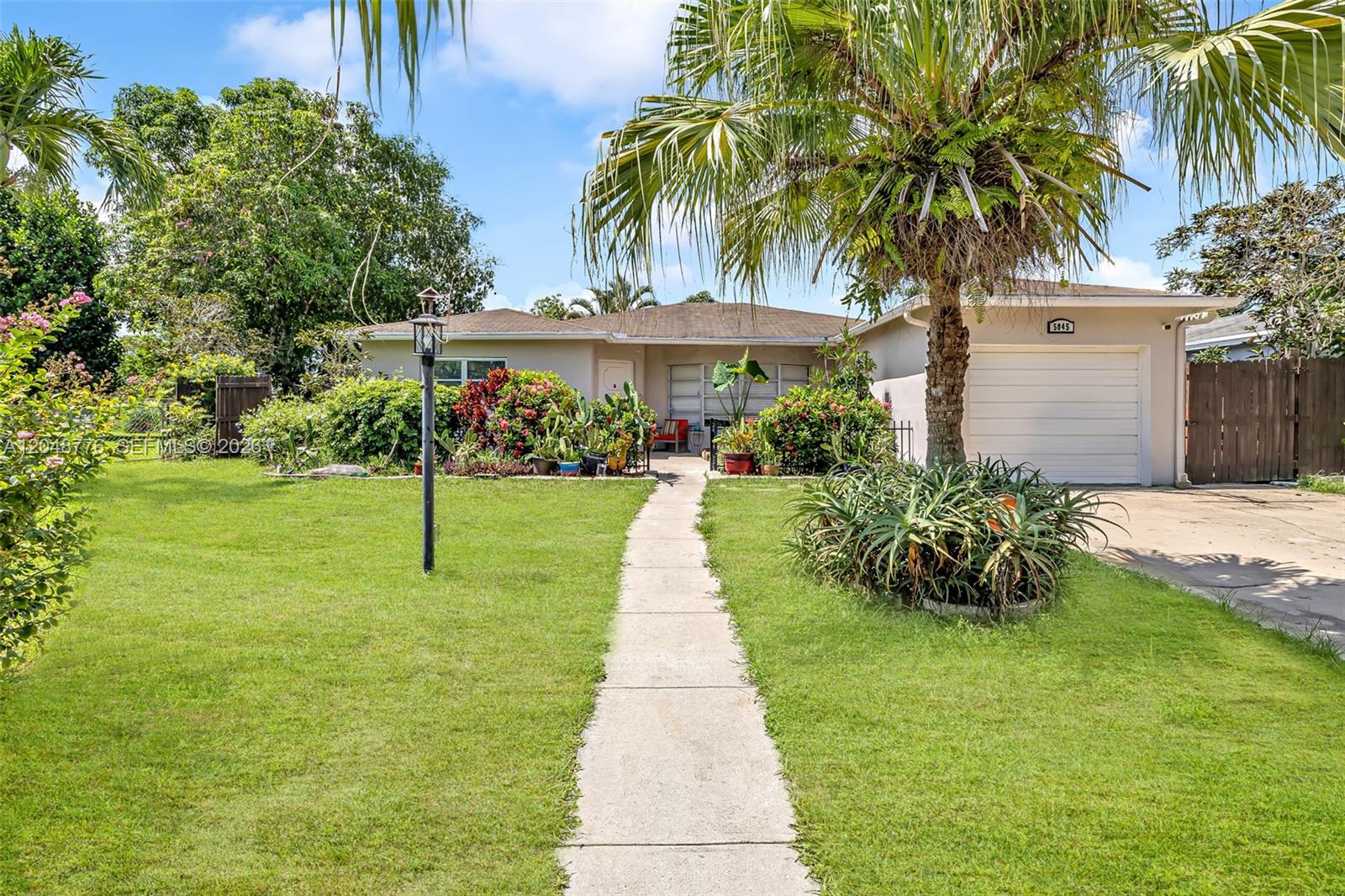 A single-story house with a white garage, a concrete walkway, and lush tropical landscaping — 5045 SW 10th St, Margate FL 33068, MARGATE, FL