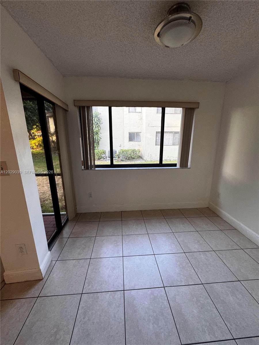 A room with light-colored floor tiles, a large window, and a sliding glass door — 9741 SW 138th Ave, Miami FL 33186, MIAMI, FL