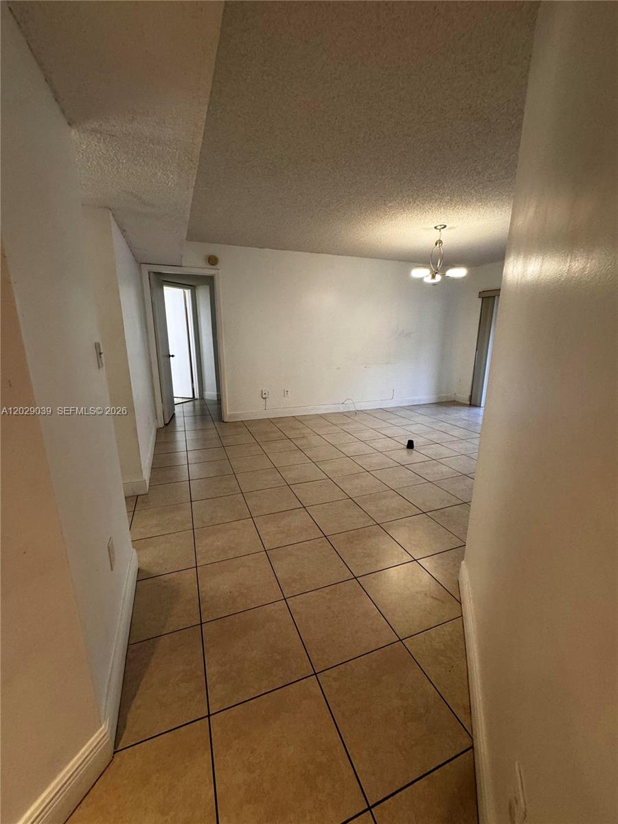 An interior view shows a living area with beige tile flooring and a ceiling light — 9741 SW 138th Ave, Miami FL 33186, MIAMI, FL