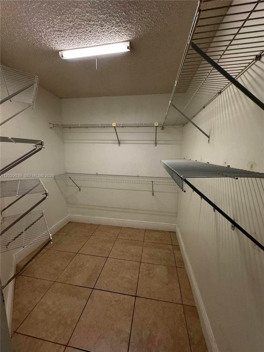 A walk-in closet features white wire shelving, tiled flooring, and a ceiling-mounted light fixture — 9741 SW 138th Ave, Miami FL 33186, MIAMI, FL