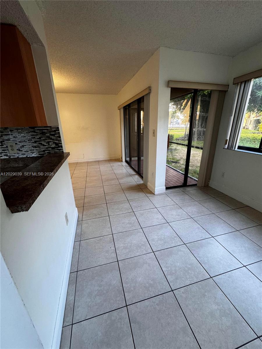 A kitchen and dining area with tile flooring, sliding glass doors, and a tiled backsplash — 9741 SW 138th Ave, Miami FL 33186, MIAMI, FL