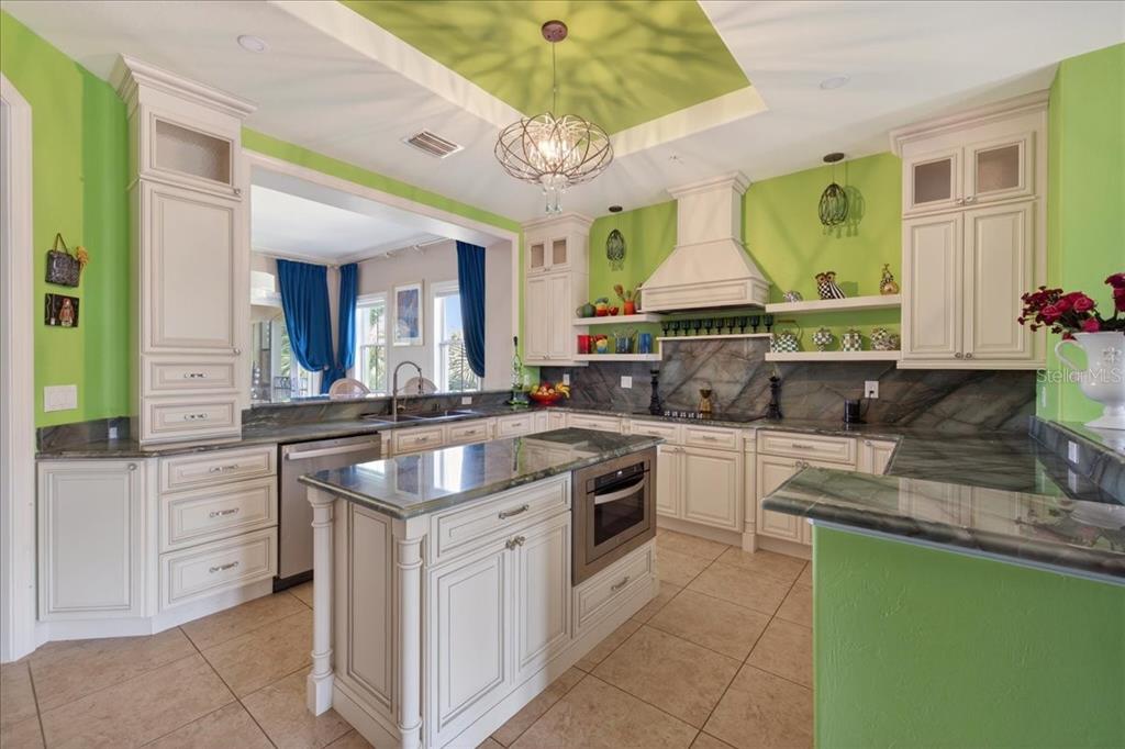 A kitchen with lime green walls, white cabinetry, dark stone countertops, and a central island — 120 AVENUE DE LA MER UNIT 1502, PALM COAST, FL