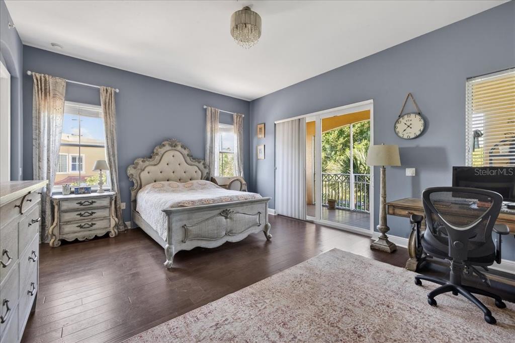 A bedroom with blue walls, a tufted bed, a desk, and a balcony sliding door — 120 AVENUE DE LA MER UNIT 1502, PALM COAST, FL