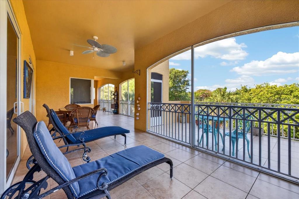 A covered balcony features tiled flooring, lounge chairs, a dining set, and a metal railing — 120 AVENUE DE LA MER UNIT 1502, PALM COAST, FL