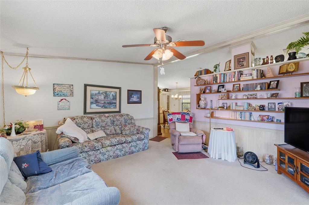 A living room features floral and blue sofas, a recliner, and built-in wall shelving — 409 TIVOLI PARK DRIVE, DAVENPORT, FL