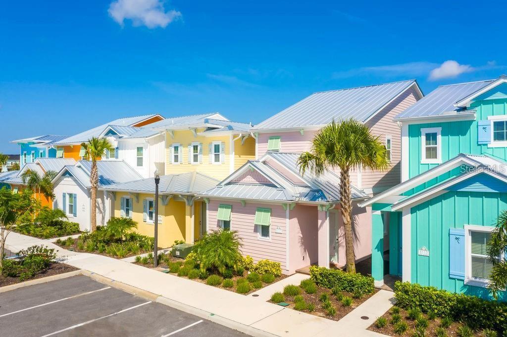 A row of colorful, pastel-colored houses with metal roofs under a bright blue sky — 8117 SURF STREET, KISSIMMEE, FL