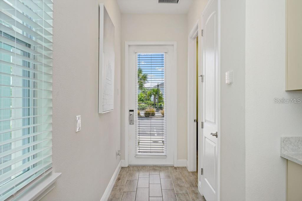 A hallway with wood-look tile flooring leads to an exterior glass door — 8117 SURF STREET, KISSIMMEE, FL