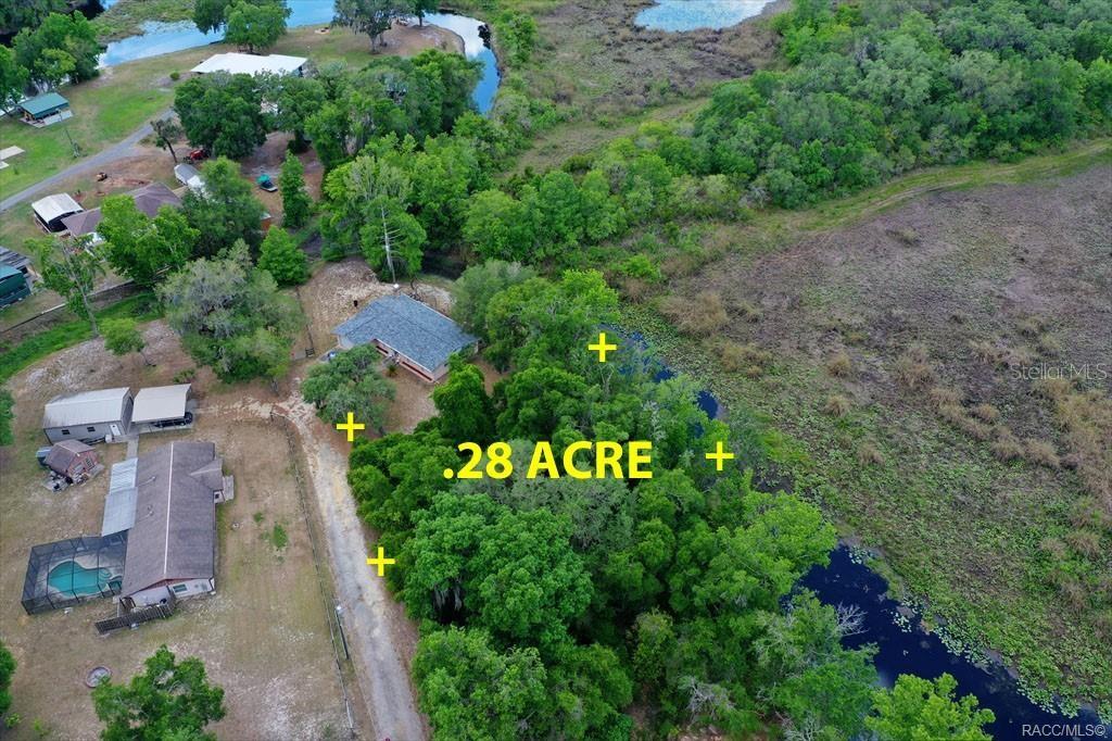 An aerial view shows a house and a wooded lot next to a waterway — 6979 E GRASS COURT, INVERNESS, FL