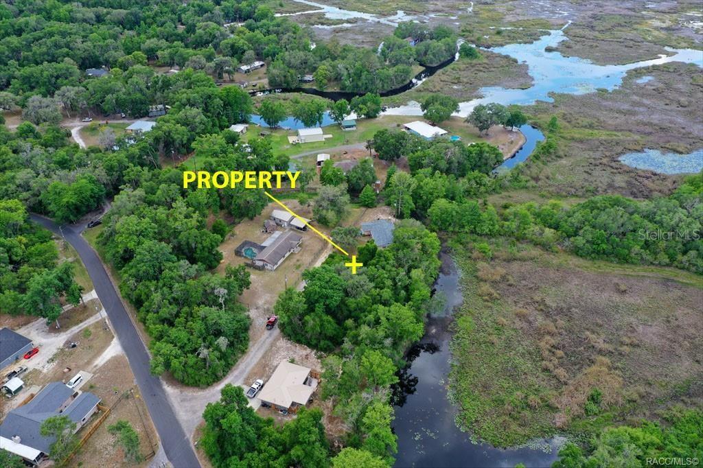 An aerial view shows a house with a pool surrounded by trees and wetlands — 6979 E GRASS COURT, INVERNESS, FL