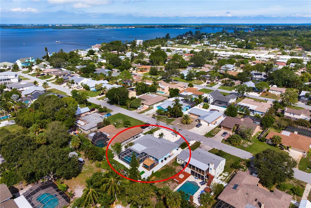 An aerial view shows a residential house with a screened-in pool in a coastal neighborhood — 7719 25TH AVENUE W, BRADENTON, FL
