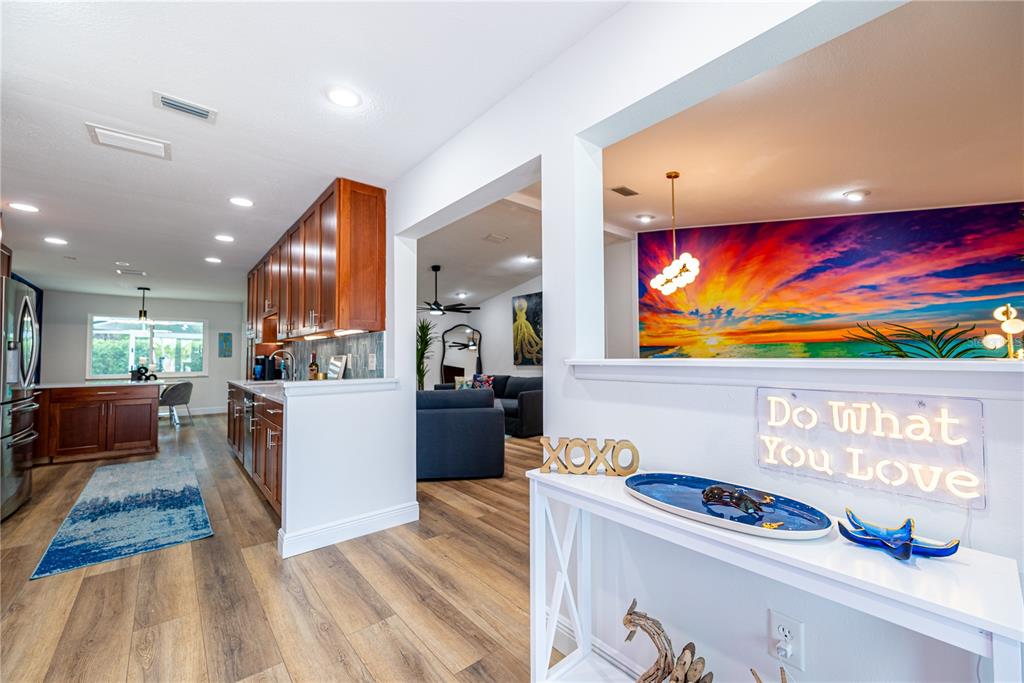 A view from a hallway into a kitchen and living area with a sunset mural — 7719 25TH AVENUE W, BRADENTON, FL