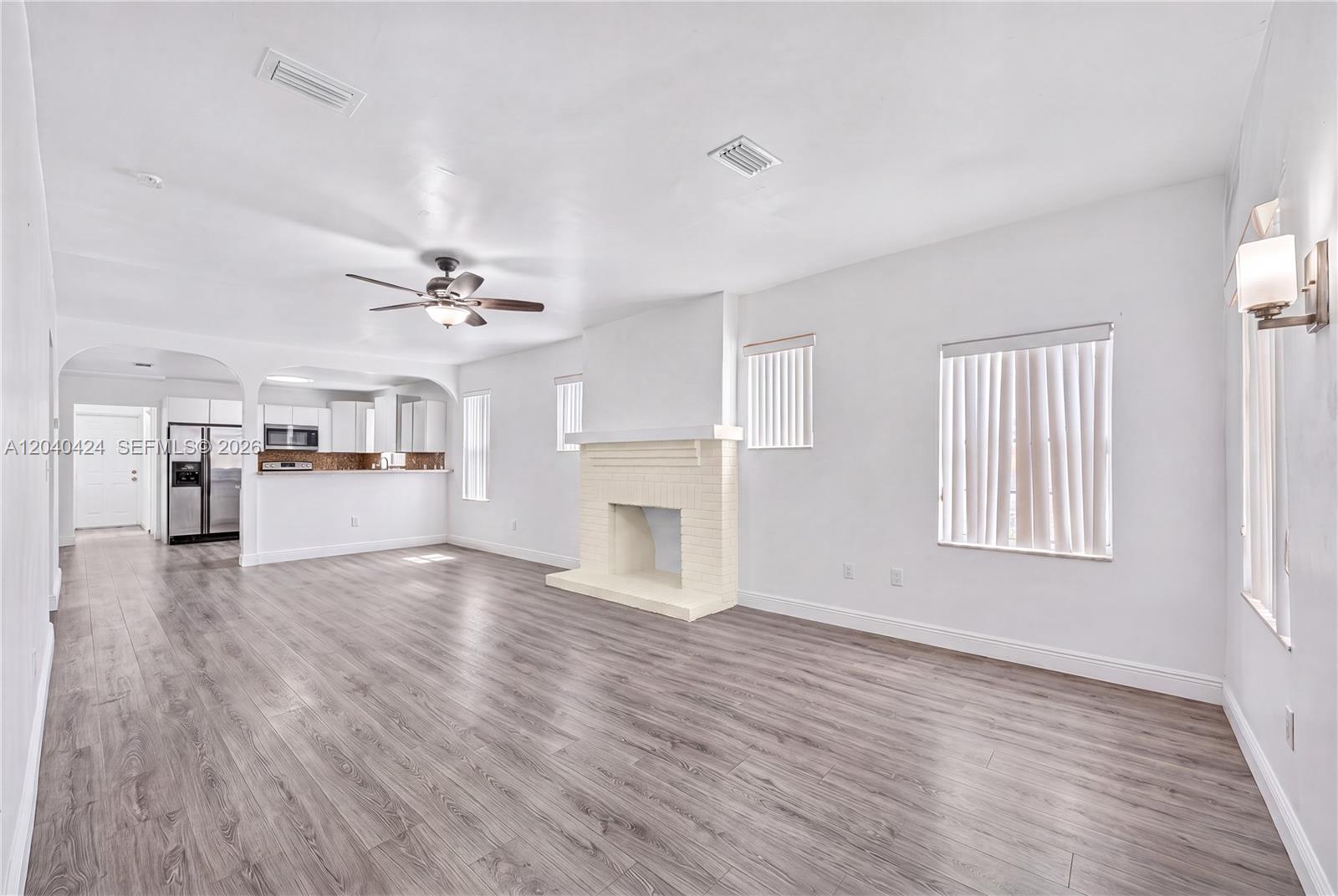 A living room features a white brick fireplace, wood-look flooring, and an adjacent kitchen area — 1168 NW 30th St # 1168, Miami FL 33127, MIAMI, FL