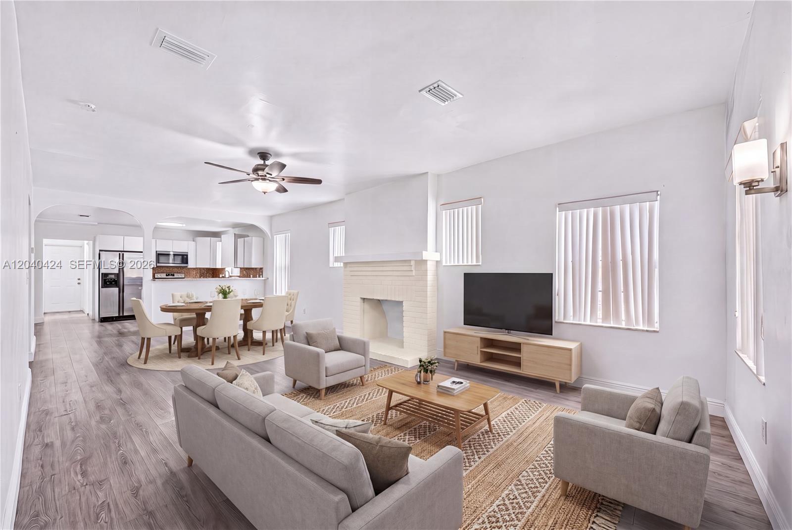 A living room and dining area feature light wood flooring, a fireplace, and neutral furniture — 1168 NW 30th St # 1168, Miami FL 33127, MIAMI, FL