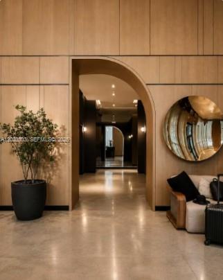 A modern lobby features light wood paneling, a large arched doorway, and a circular wall mirror — 121 NE 5th St # 3203, Miami FL 33132, MIAMI, FL