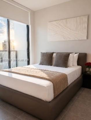 A bedroom features a bed with a brown frame, neutral bedding, and a large window — 121 NE 5th St # 3203, Miami FL 33132, MIAMI, FL