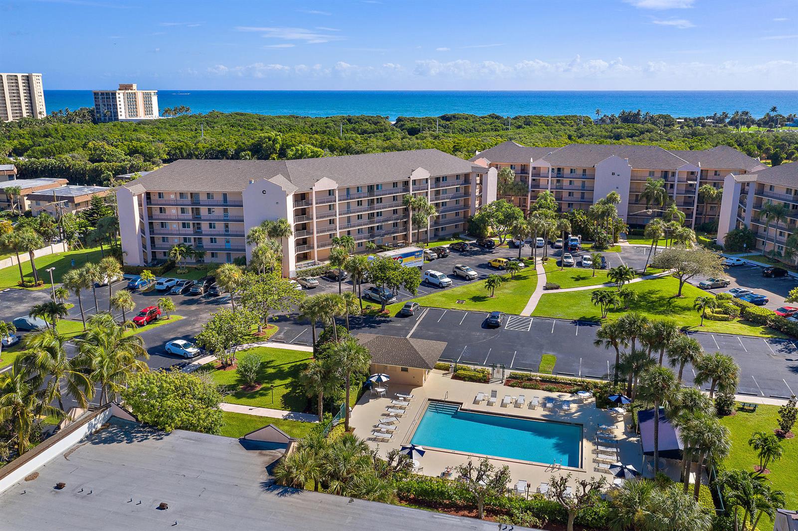 An aerial view shows a multi-story apartment complex with a swimming pool and parking lot — 275 Palm Avenue # C201, Jupiter FL 33477, JUPITER, FL