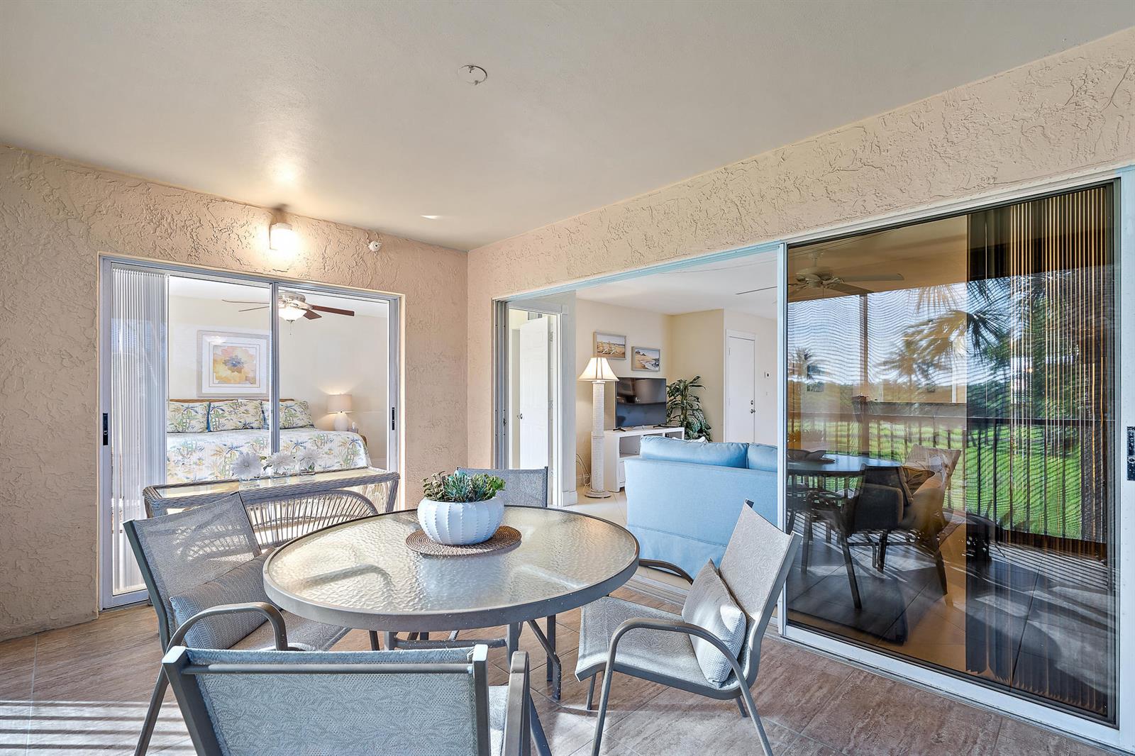 A covered patio features a glass-topped dining table and chairs, overlooking a living room interior — 275 Palm Avenue # C201, Jupiter FL 33477, JUPITER, FL