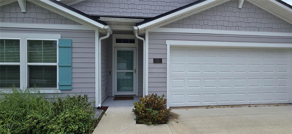 The exterior of a single-story house features gray siding, a garage, and a front entrance — 32 ROYAL OAK DRIVE, PALM COAST, FL