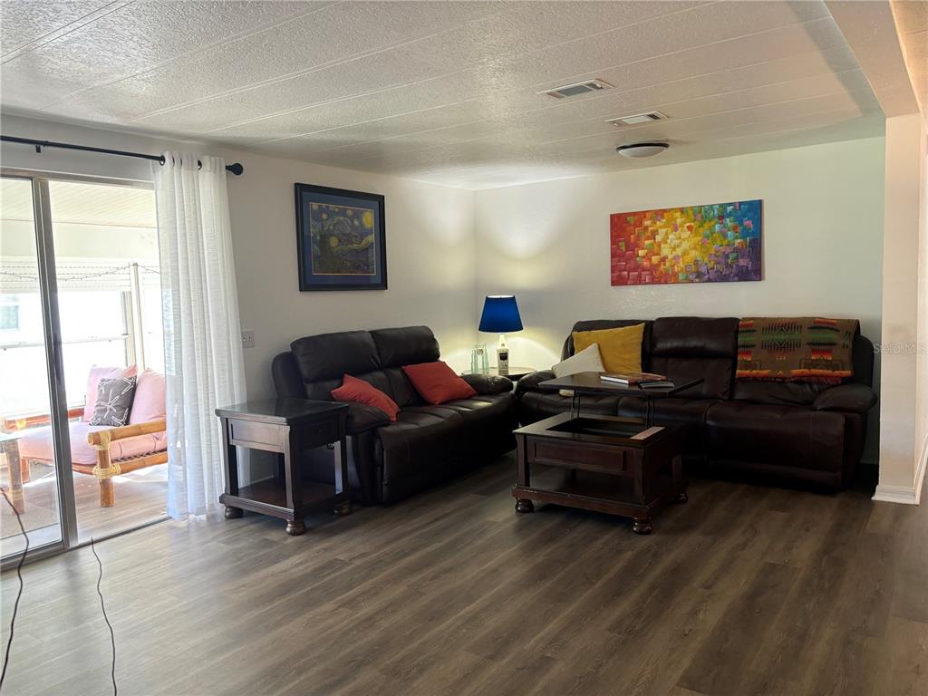 A living room features dark leather sofas, a wooden coffee table, and wood-look flooring — 4325 WATER OAK LANE UNIT 54, ZELLWOOD, FL