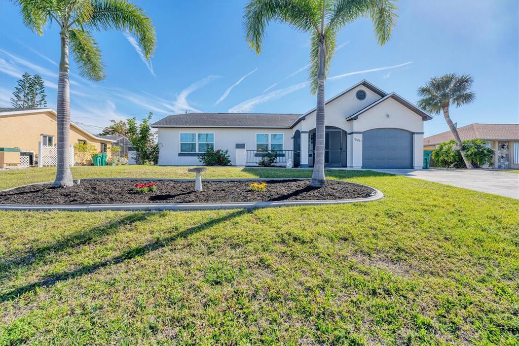 A single-story house with a garage, palm trees, and a landscaped front yard — 18091 EAU GALLIE CIRCLE, PORT CHARLOTTE, FL