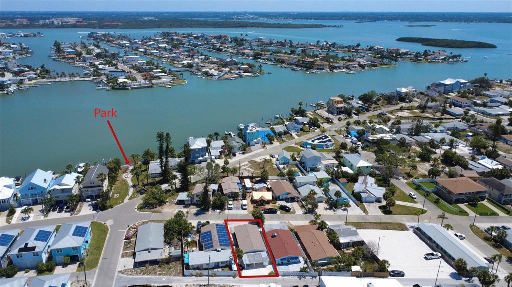 An aerial view shows a residential neighborhood with a highlighted house near a waterfront park — 13440 1ST STREET E, MADEIRA BEACH, FL