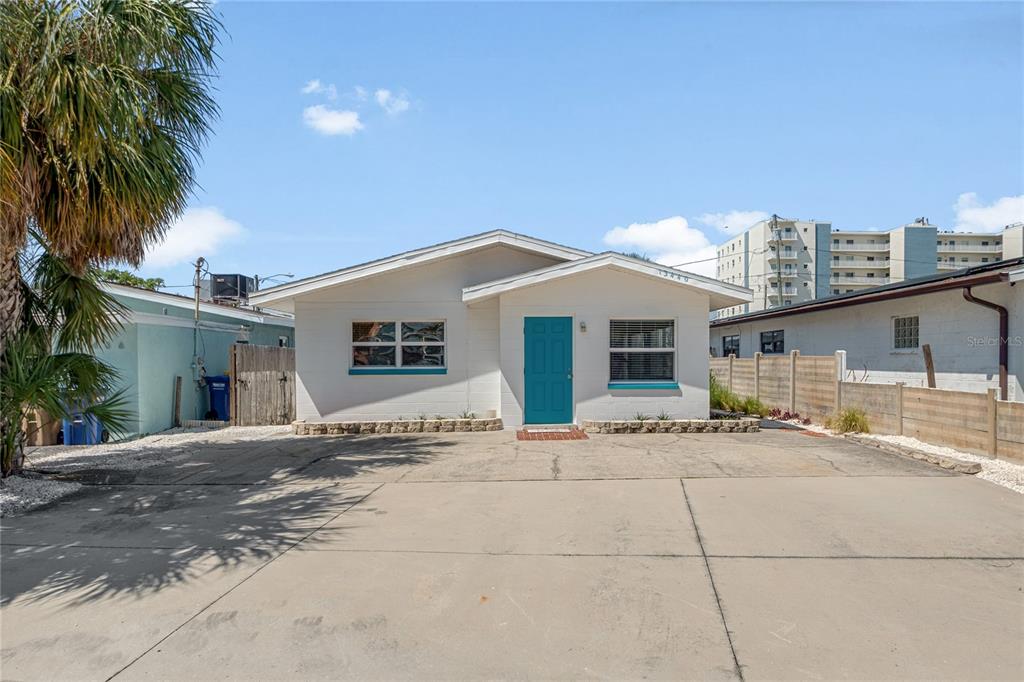 A single-story white house with a teal front door and a large concrete driveway — 13440 1ST STREET E, MADEIRA BEACH, FL