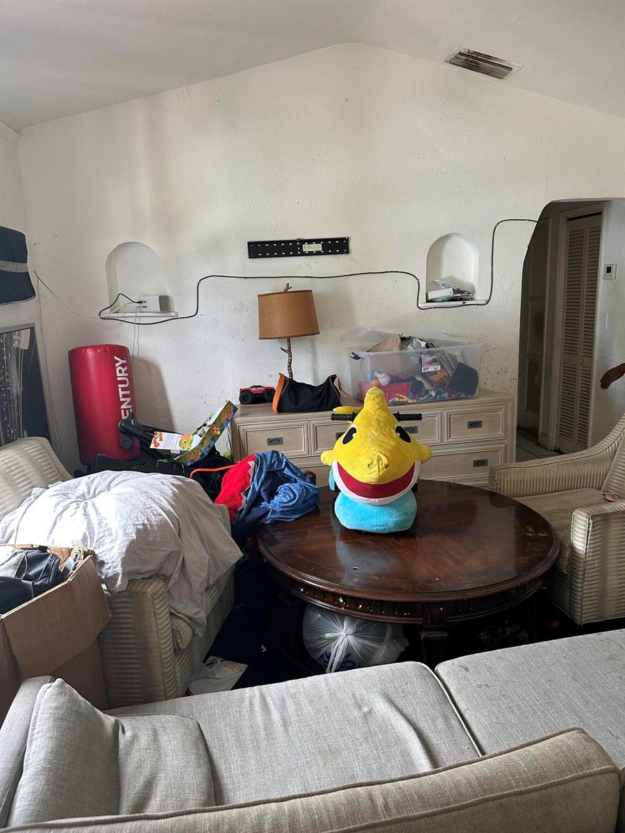 A cluttered living room features a round wooden coffee table, two armchairs, and a dresser — 2114 Dewey Street, Hollywood FL 33020, HOLLYWOOD, FL