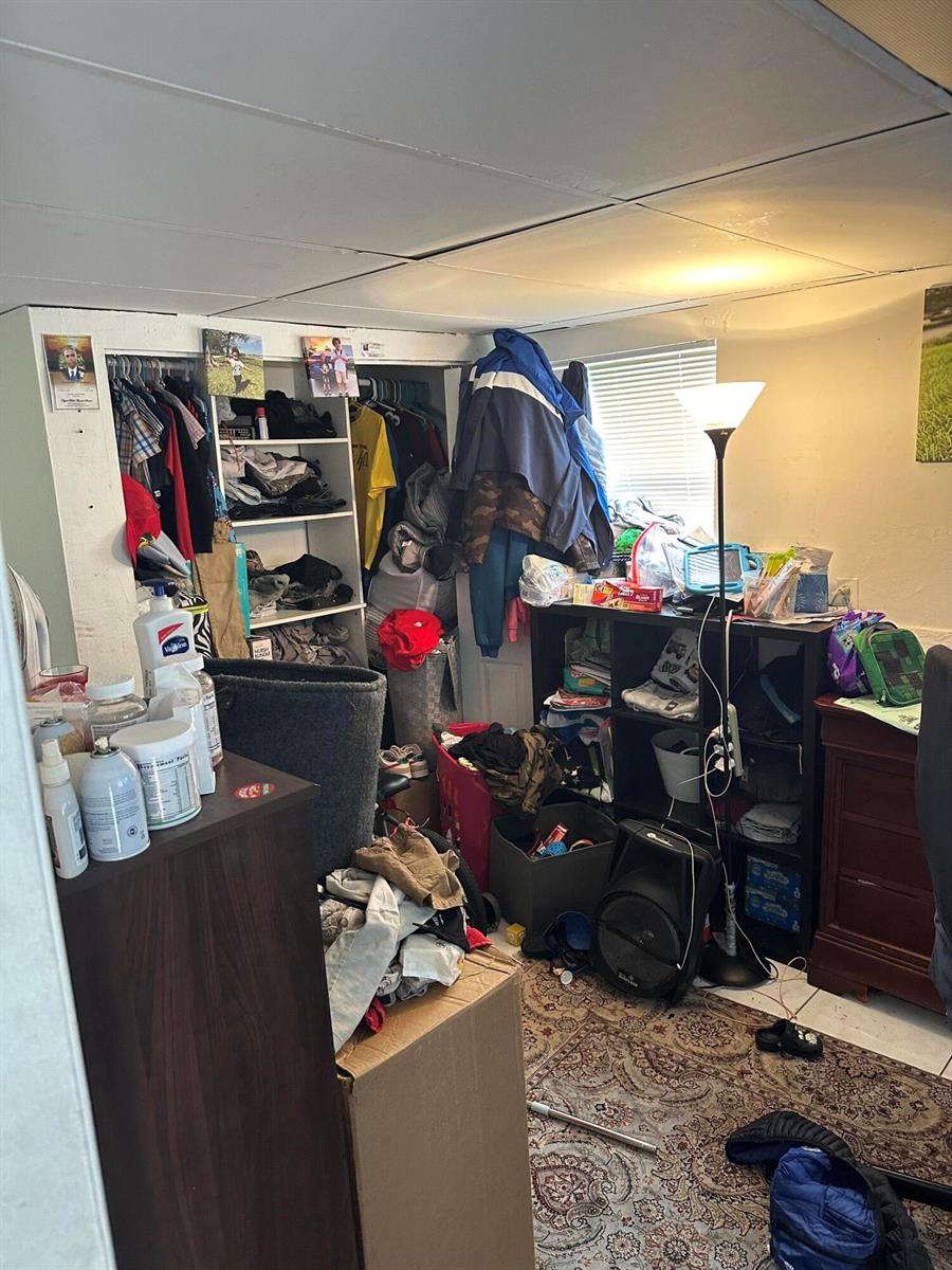 A cluttered bedroom features a closet with open shelving, a black storage unit, and a rug — 2114 Dewey Street, Hollywood FL 33020, HOLLYWOOD, FL